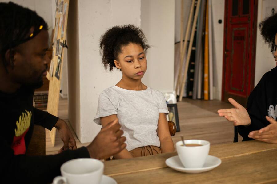 A family having a serious conversation at a table with coffee cups, highlighting a tense atmosphere indoors