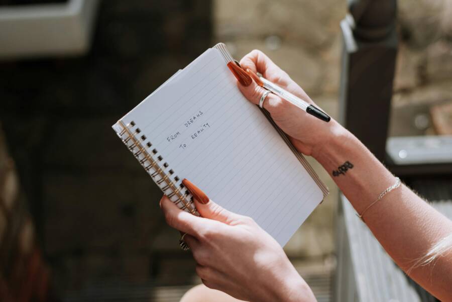 A woman writes in a notebook about dreams, a mirror image of turning dreams into reality