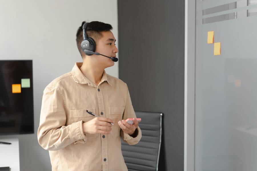 Professional Asian man working in call center holding pen and smartphone