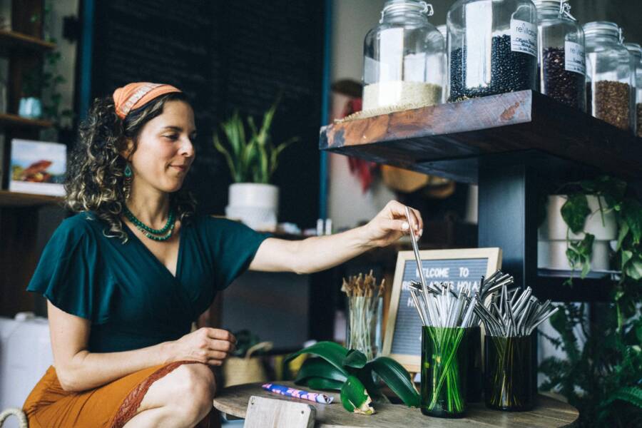 Woman selecting reusable metal straws in a sustainable store environment.