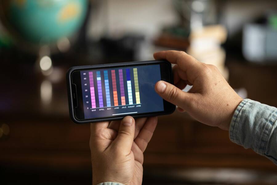 Close-up of hands holding a smartphone displaying a colorful bar graph