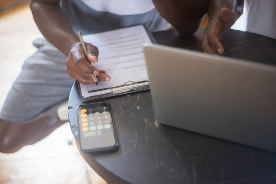 A person using a smartphone with a notebook on a round table