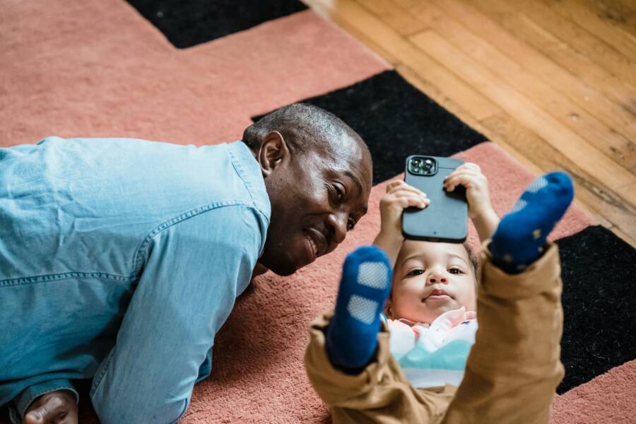 Stop Your Child From Turning Off Parental Controls on a Smartphone A father and child thumbs up while reviewing phone settings
