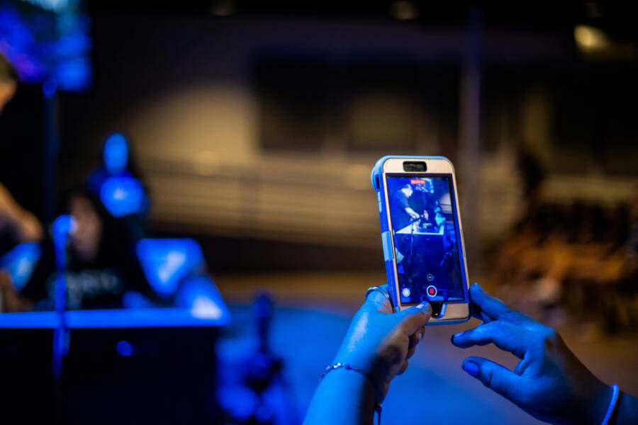 Close-up of hands capturing a scene with a smartphone in a dimly lit environment