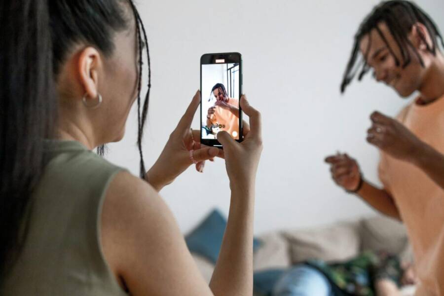 Two friends enjoying a fun, indoor vlogging session, capturing candid moments on a smartphone