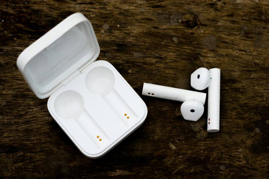 Close-up of wireless earbuds and charging case on wooden surface