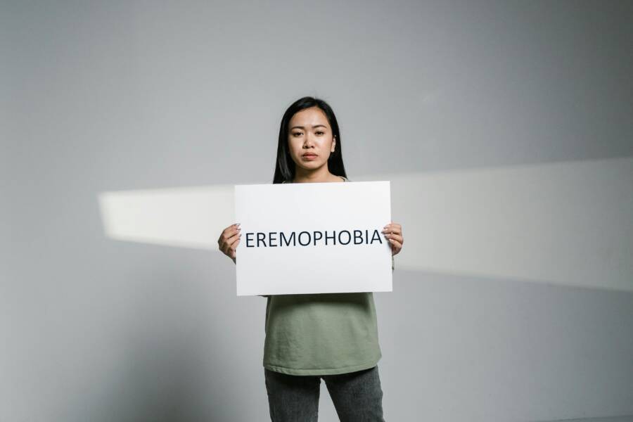 A woman in a studio holds a sign reading