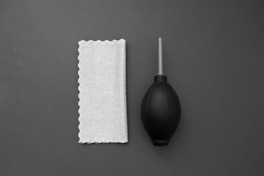 Overhead view of a camera cleaning blower and microfiber cloth on a gray background.