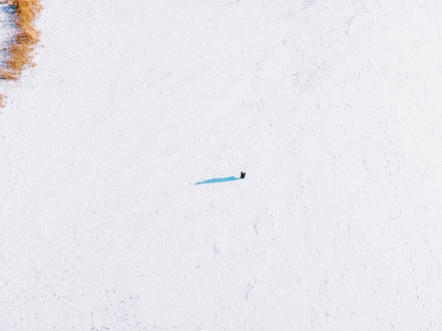 Aerial shot of a solitary figure on a vast snowy field in Harbin, China, capturing winter