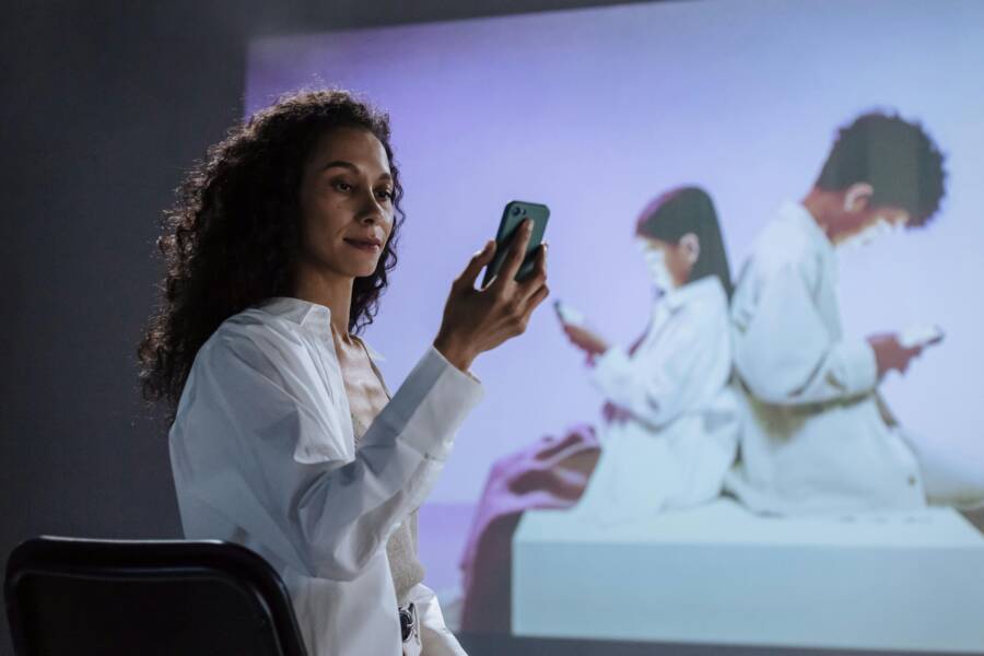 A mother studies her children engrossed in smartphones, highlighting digital safety.