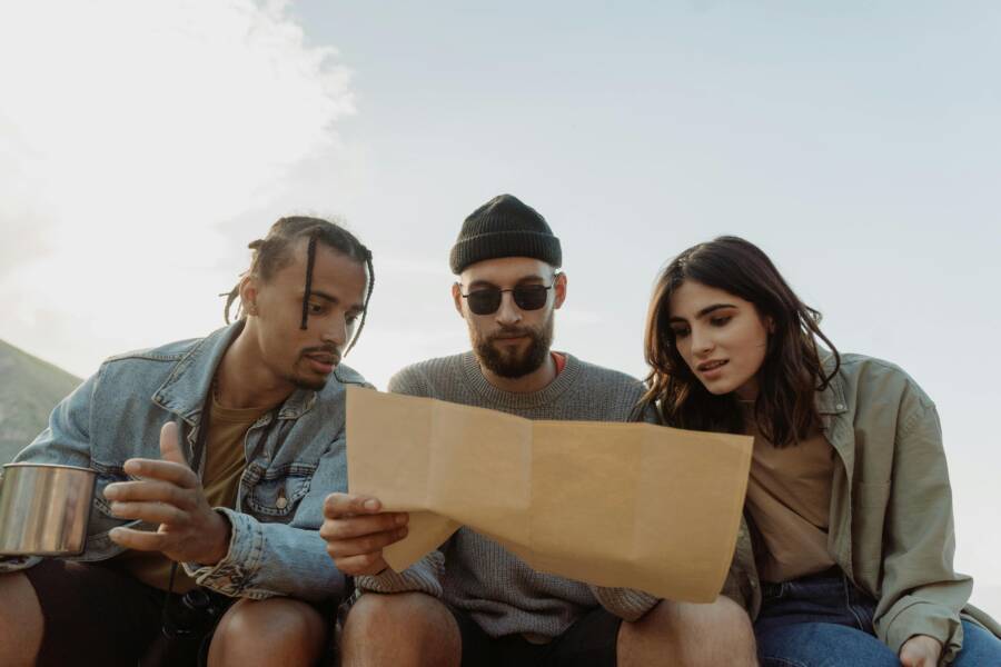 Group of diverse friends reading a map outdoors, exploring and planning their adventure