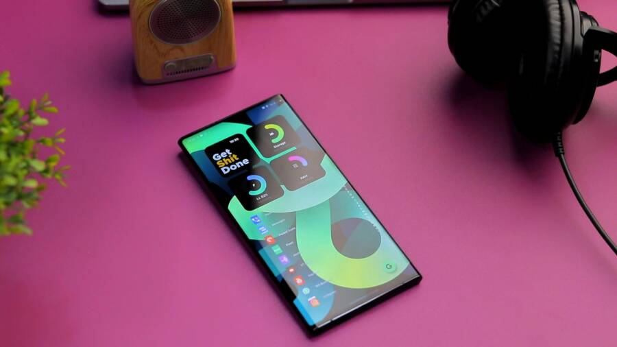 Top-down view of a smartphone, speaker, and headphones on a vibrant pink surface, perfect for tech-themed designs.